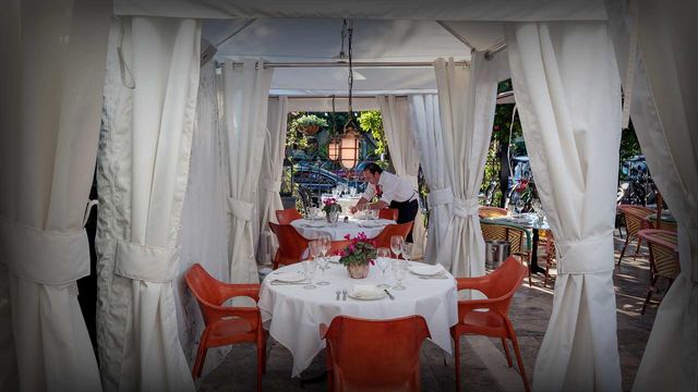 A white-curtained cabana table set for dinner at The Continental on Fifth Avenue South