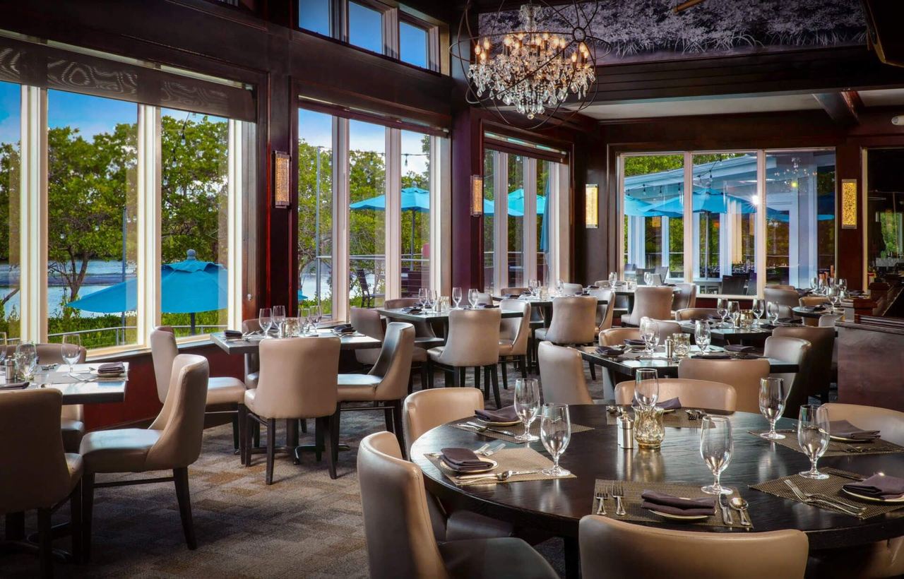 The Bay House dining room, with tall windows onto the Cocohatchee River