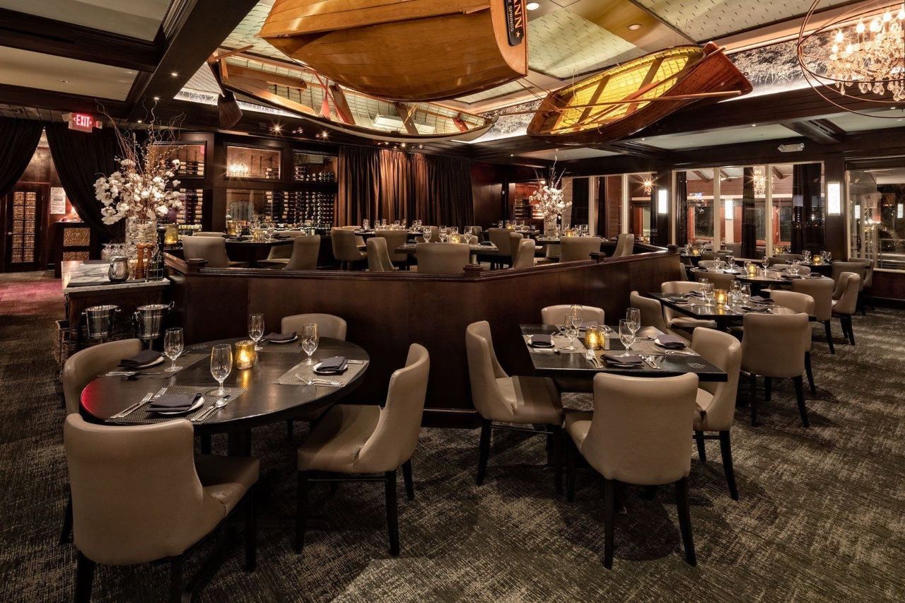 The Bay House dining room at night, with wooden canoes hung from the ceiling